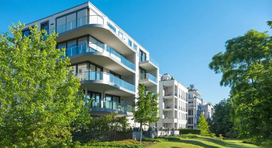 Moderne Wohngebäude mit Balkonen und Glasgeländern, umgeben von Grünflächen. Hier wird in Recklinghausen gebaut.
