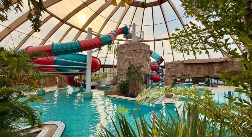Buntes Rutschenparadies im **Dorsten Freibad** unter einem Glasdach. Türkises Wasser lädt zum Planschen ein.