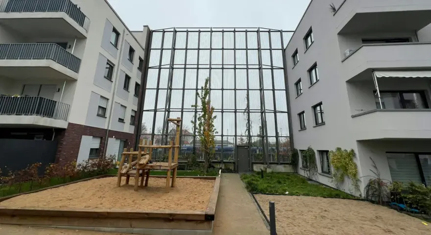 Moderne Wohnanlage mit Spielplatz und Sandkasten. Die Fassaden und Balkone sind hellgrau. Die Immobilienpreise in Leverkusen spiegeln die Attraktivität der Stadt wider.