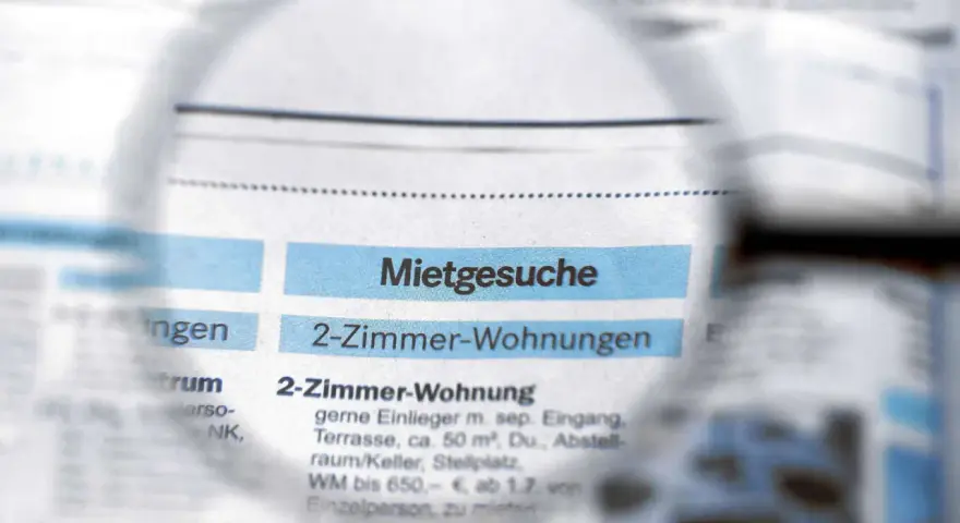 Lupe über Zeitungsanzeigen mit "Mietgesuche" und "2-Zimmer-Wohnungen". Ein Blick auf den Mietspiegel Moers.