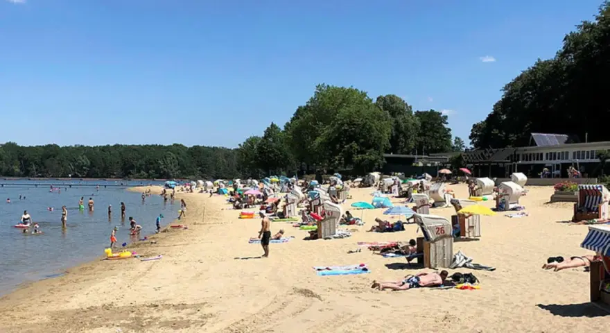 Sonniger Tag am **Haltern am See Strand** mit vielen Badegästen, Strandkörben und Bäumen im Hintergrund.