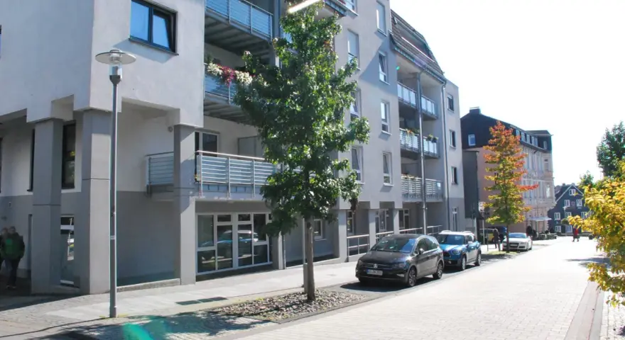 Moderne Wohngebäude mit Balkonen und Autos auf der Straße. Ein Baum steht vor einem Gebäude. Informationen zum Mietspiegel Wermelskirchen sind hier nicht ersichtlich.