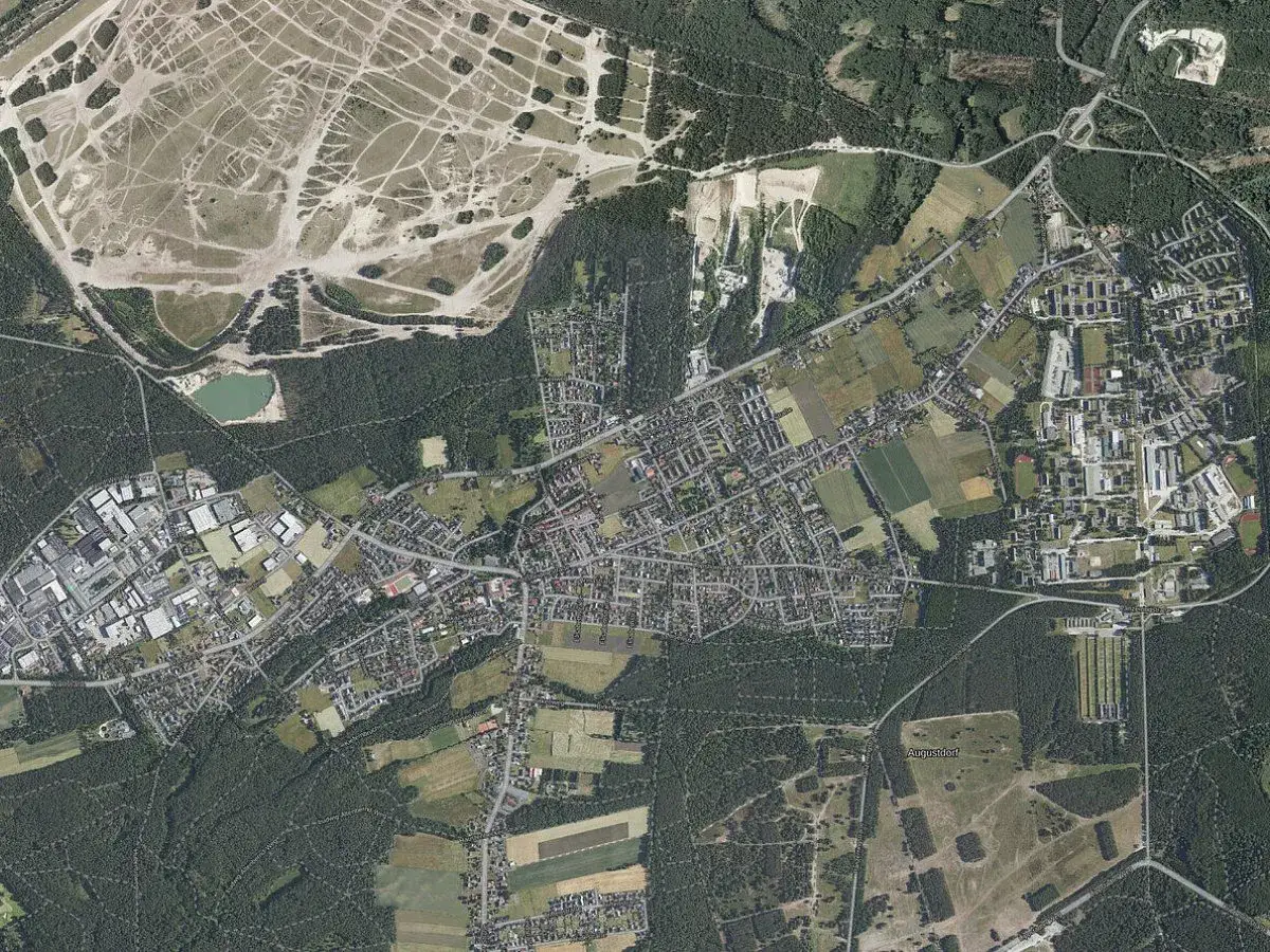 Luftaufnahme von Augustdorf mit Wohngebieten, Industrieanlagen und einem gro&szlig;en, offenen Gel&auml;nde. Hier finden Sie Informationen zum Mietspiegel Augustdorf.
