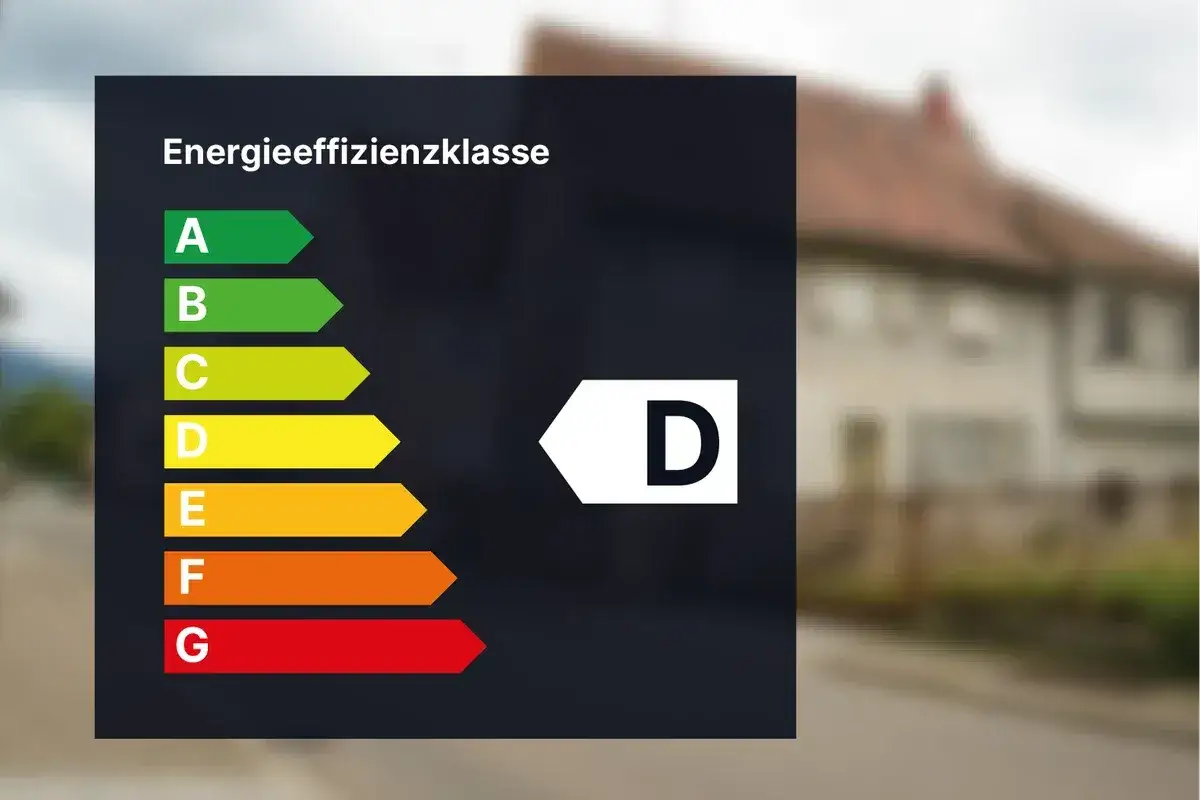 Energieeffizienzklasse D auf einem dunklen Hintergrund. Ein Haus ist unscharf im Hintergrund zu sehen.