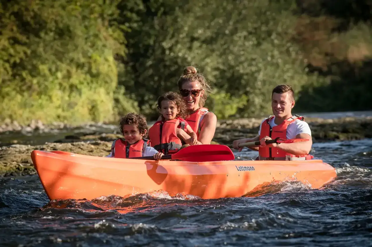 Familie genie&szlig;t eine Fahrt im orangefarbenen Kanu auf der Lippe.