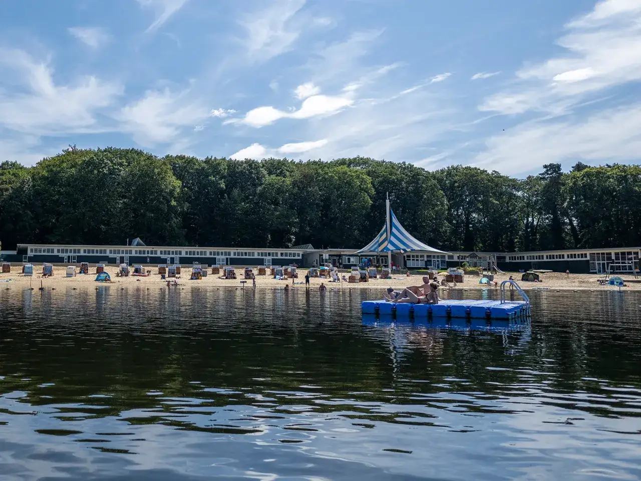 Entspannter Tag am haltern am see strand. Menschen genie&szlig;en die Sonne auf Strandk&ouml;rben und einer schwimmenden Plattform.
