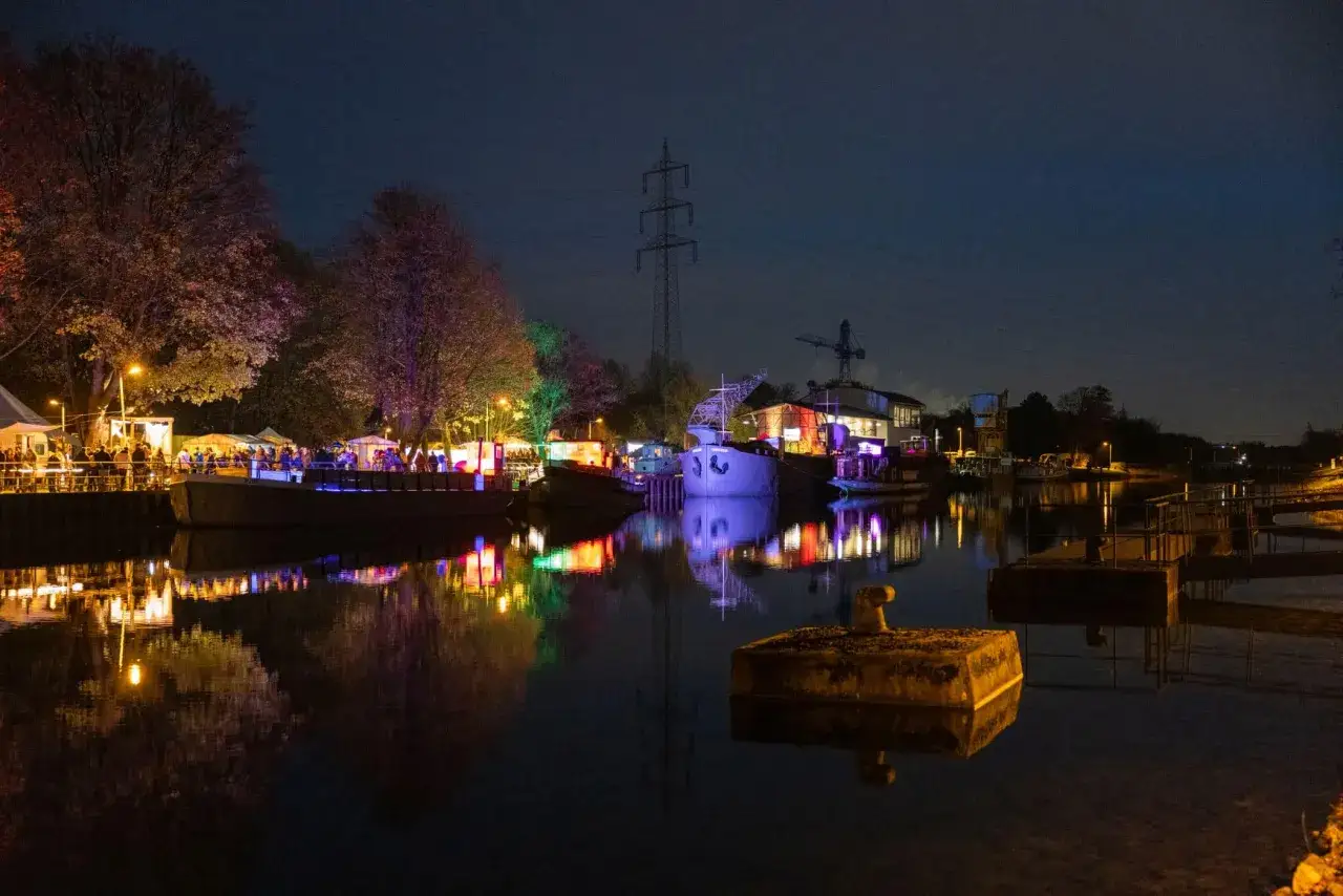Buntes Lichtermeer am weihnachtsmarkt schiffshebewerk henrichenburg. Boote und B&auml;ume spiegeln sich im Wasser.