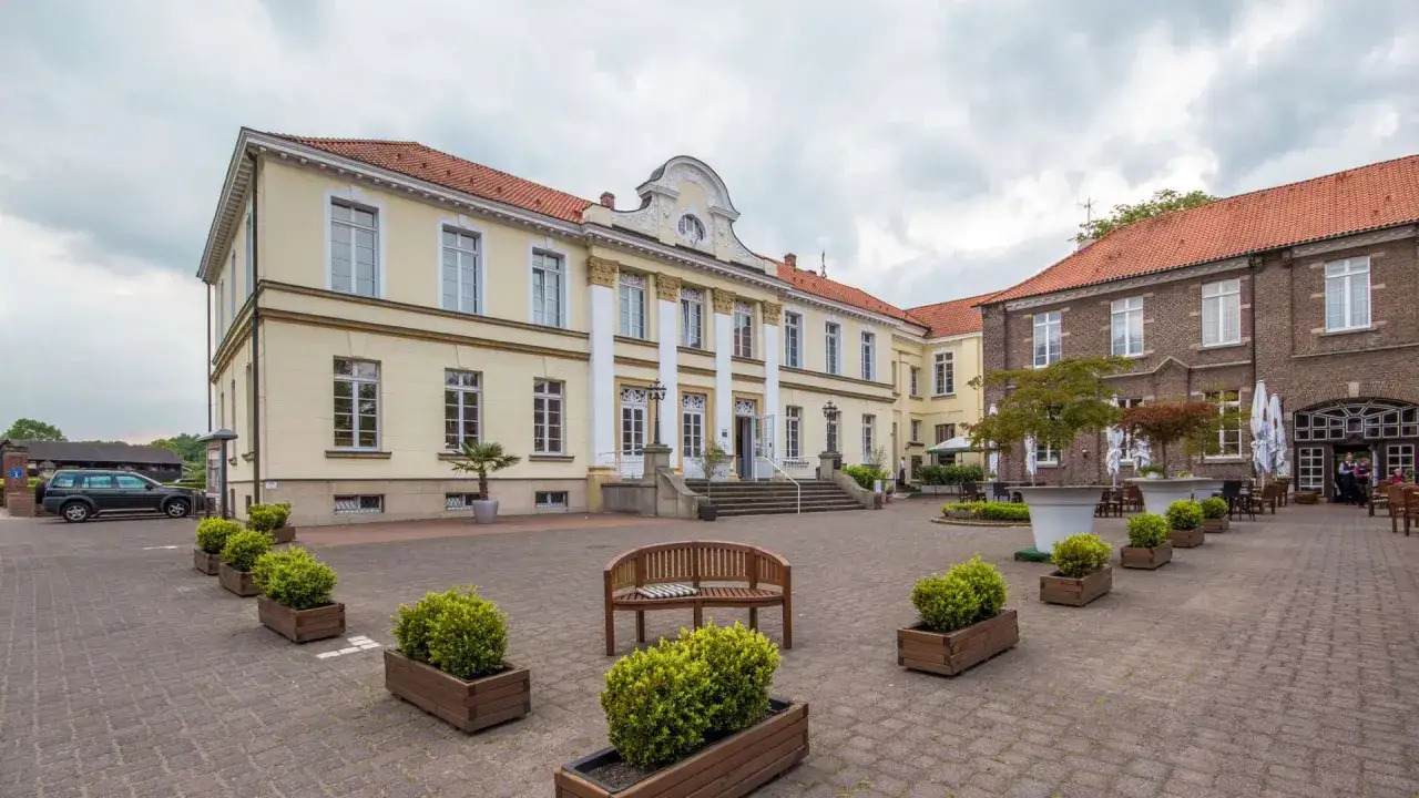 Das Schloss Westerholt, ein gelbes Herrenhaus mit S&auml;ulen, und ein Backsteingeb&auml;ude mit Au&szlig;ensitzpl&auml;tzen.