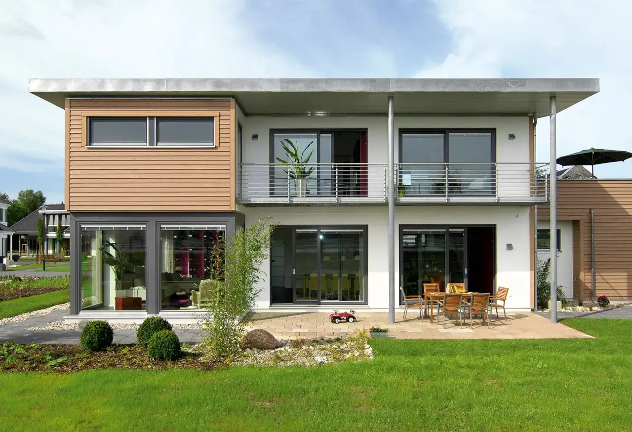 Modernes kleines Haus mit Holzverkleidung und einer großzügigen Dachterrasse. Ein Garten mit Rasen und Büschen lädt zum Entspannen ein.