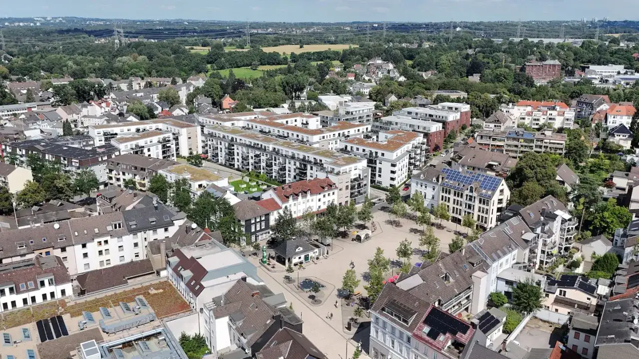 Luftaufnahme eines Stadtplatzes mit modernen Wohngebäuden und Bäumen. Die Vielfalt der Architektur deutet auf unterschiedliche immobilienpreise Solingen hin.