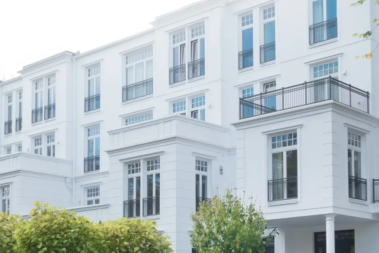 Modernes Mehrfamilienhaus mit wei&szlig;en Fassaden und Balkonen. Ideal, wenn Sie ein Mehrfamilienhaus verkaufen m&ouml;chten.