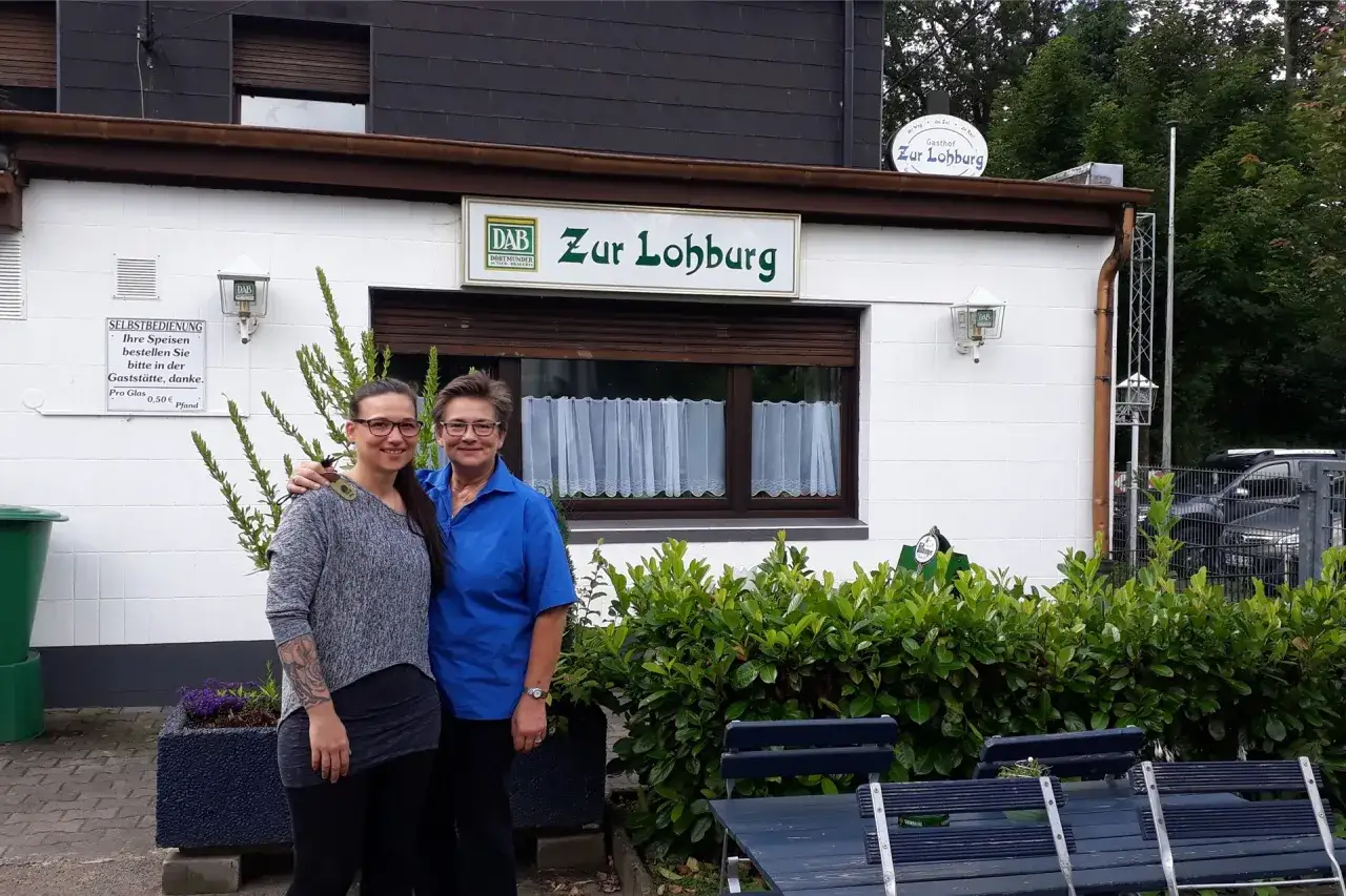 Zwei Frauen vor dem Gasthof Zur Lohburg in Waltrop. Ein Schild weist auf Selbstbedienung hin.