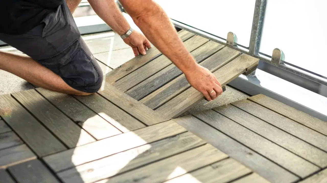 Mann verlegt Holzfliesen als bodenbelag balkon mietwohnung. Einfach und schnell zu verlegen.