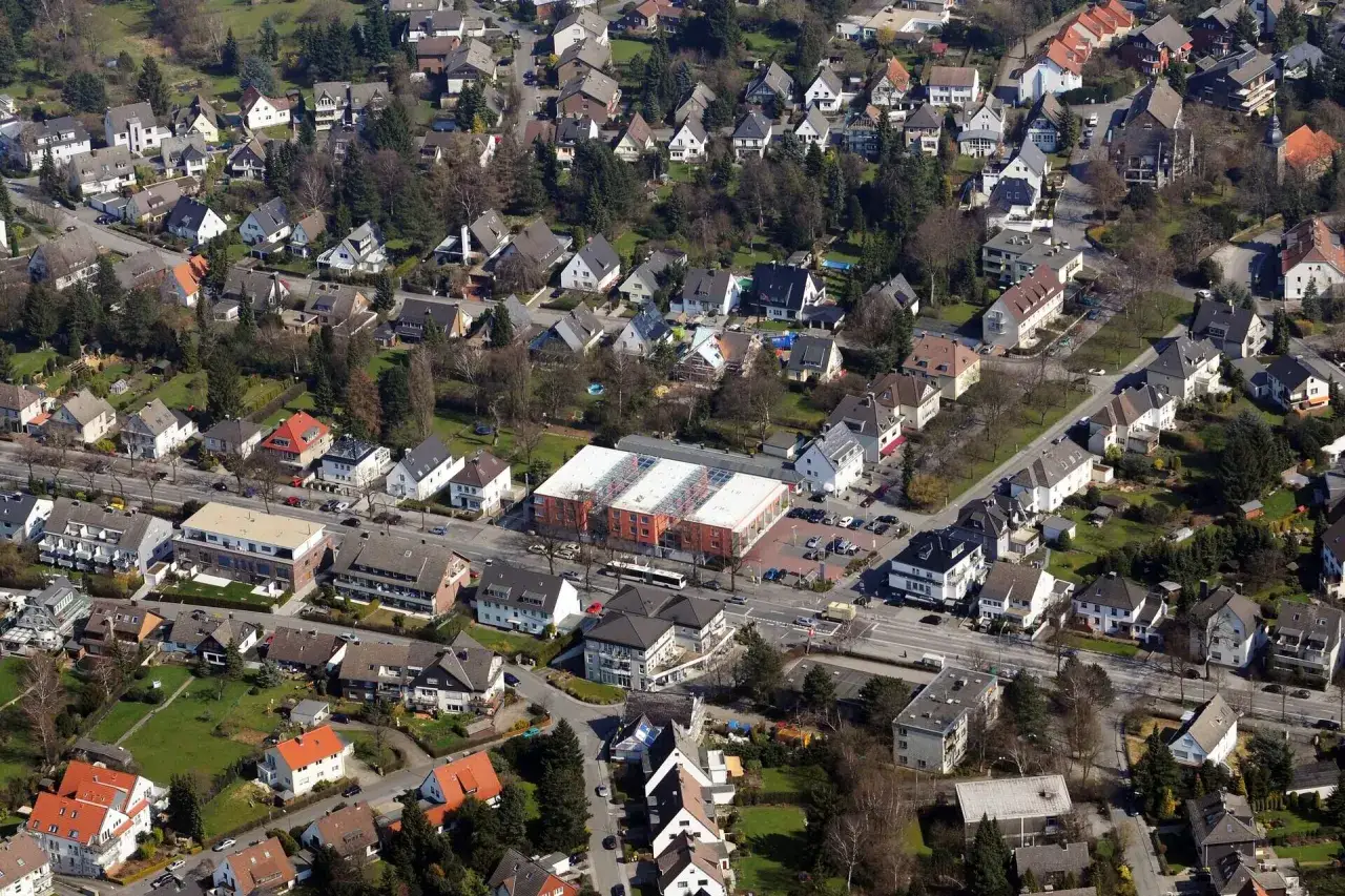 Luftaufnahme eines Wohngebiets in Dortmund. Viele Einfamilienhäuser und einige Mehrfamilienhäuser prägen das Bild. Der Wohnungsmarkt Dortmund zeigt sich hier von seiner grünen Seite.