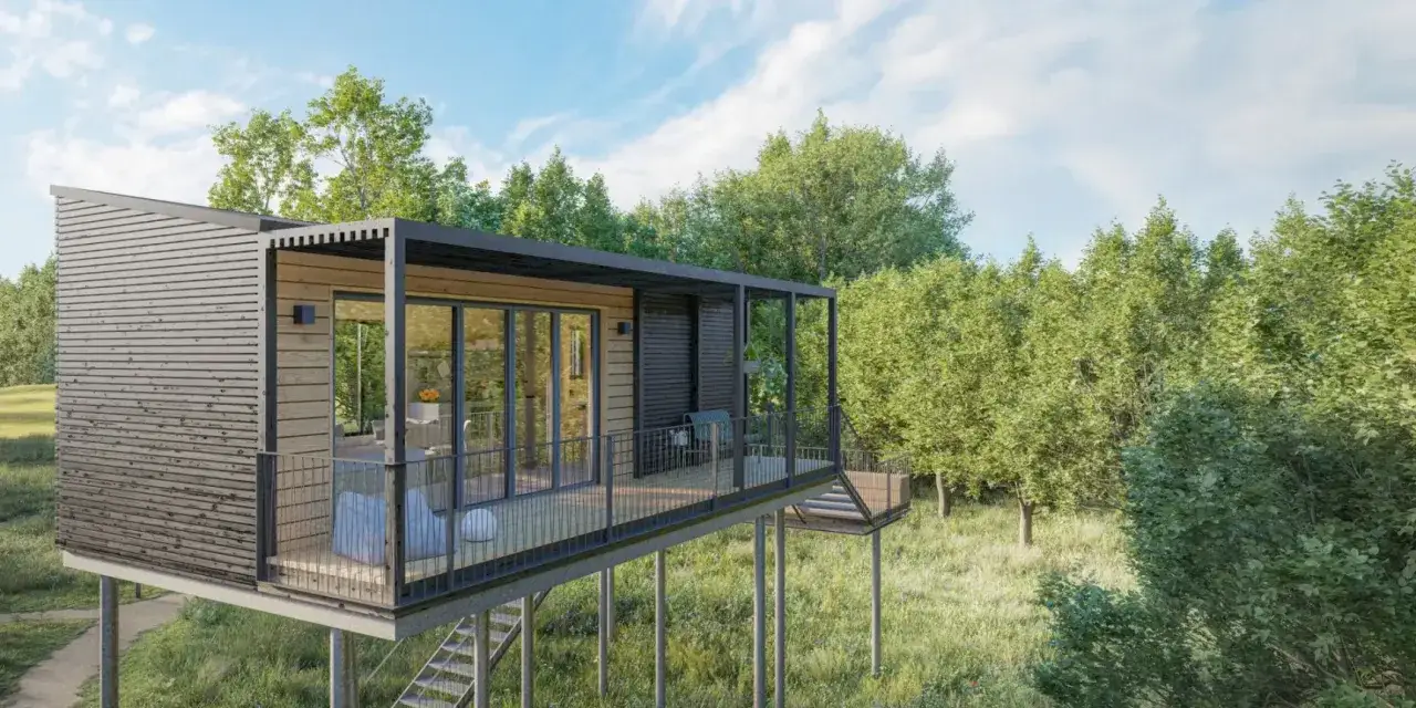 Modernes Baumhaus zum Wohnen, auf Stelzen in einem Wald, mit Terrasse und Glasfront.