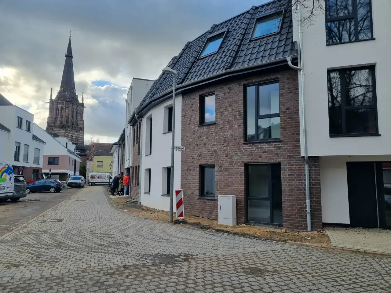 Neubau in Erkelenz mit Kirche im Hintergrund. Hier könnte bald der Mietspiegel Erkelenz für die neuen Wohnungen relevant werden.