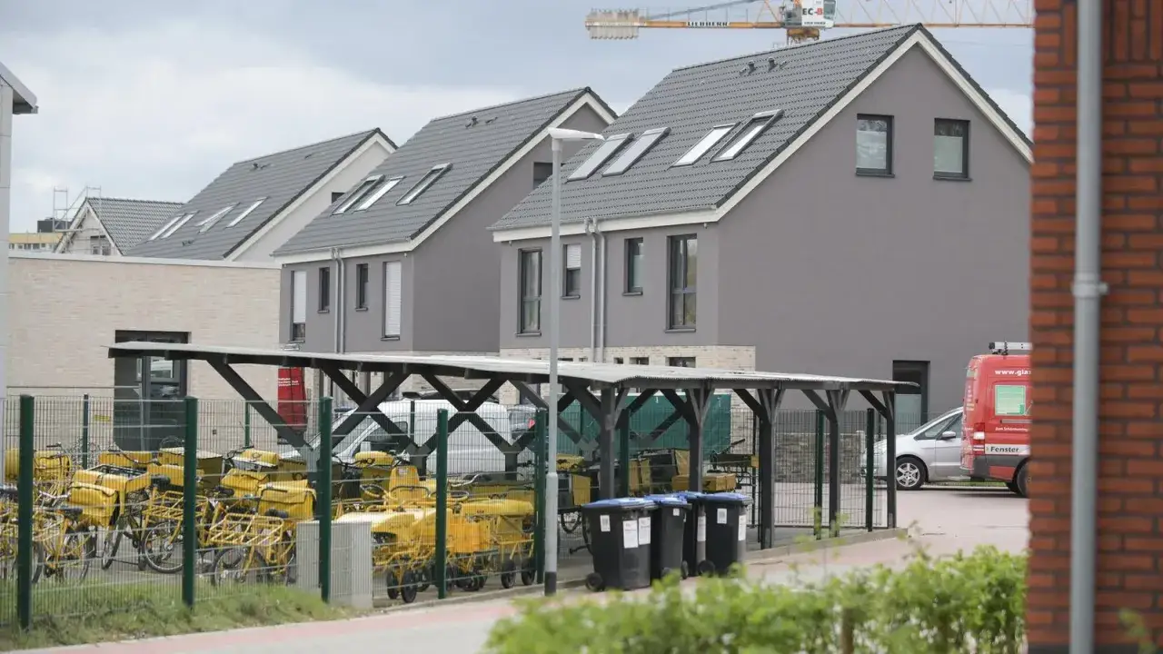 Reihenh&auml;user in Moers mit vielen gelben Lastenr&auml;dern unter einem Carport. Ein roter Lieferwagen steht daneben.