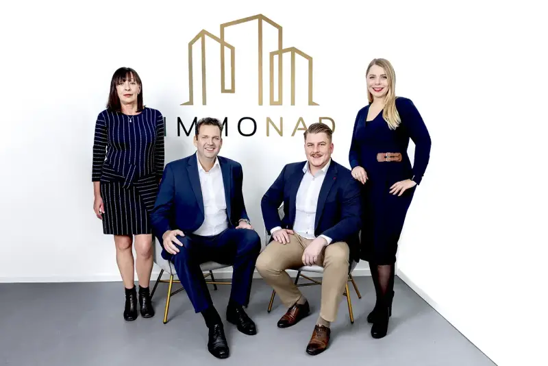 Immobilienpreise Oberhausen: Vier professionelle Makler des Unternehmens "MMONAD" posieren vor ihrem Logo.